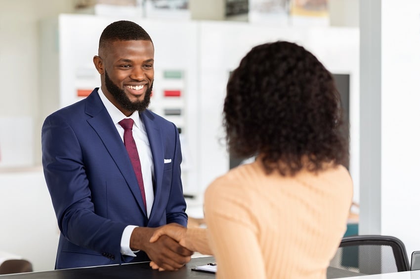 smiling-car-seller-shaking-hands-with-female-custo-2022-12-16-07-10-38-utc